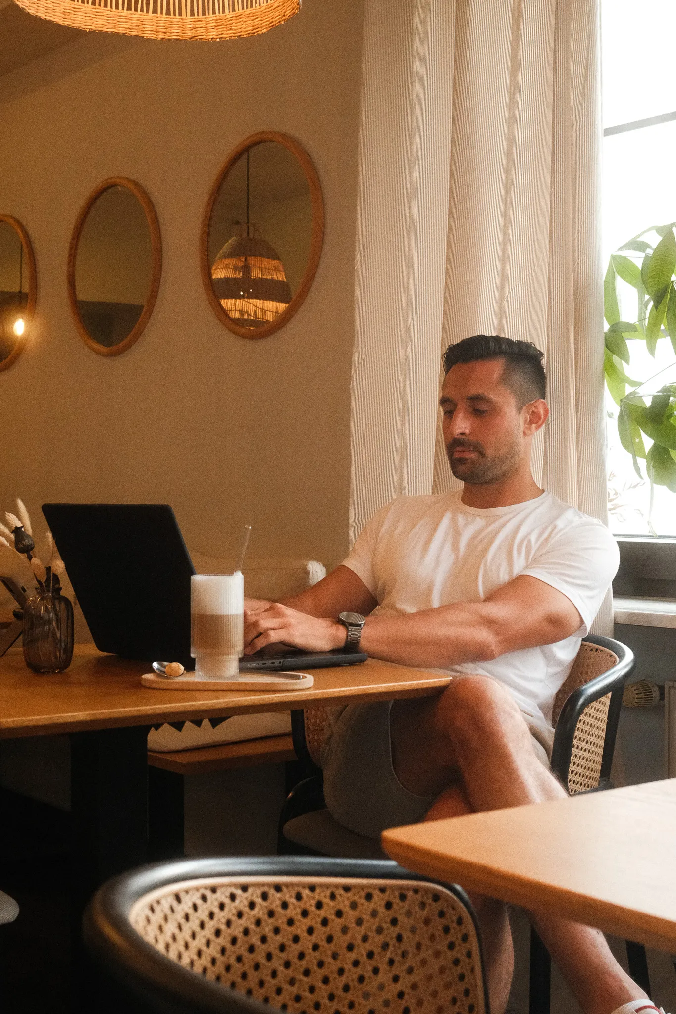 Gast arbeitet konzentriert an seinem Laptop im Neo Café Deli in Ramstein, mit Eiskaffee am Tisch und gemütlicher Atmosphäre im Hintergrund